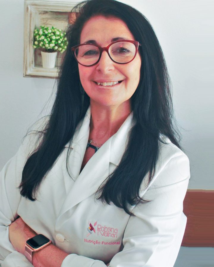 Robena Molinari, nutricionista funcional, sorrindo de jaleco branco em seu consultório